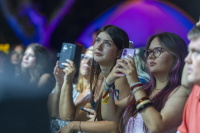 Junge Konzertbesucherinnen stehen am Bühnenrand und filmen den Auftritt mit ihren Smartphones.