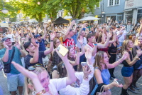Ein Publikum in der Altstadt klatscht und hebt bei Sonnenschein die Arme vor einer Bühne.