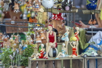 Kunsthandwerkliche Figuren, Tiere und Windspiele sind an einem Marktstand dekorativ aufgebaut.
