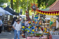 Bunte Metallfiguren und Sonnenmotive hängen an einem Marktstand im Freien.