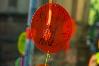 Ein orangefarbener Kreis einer Kunstinstallation hängt im Vordergrund und trägt eine handschriftliche Botschaft zu Gesundheit, Kreativität und Mut.