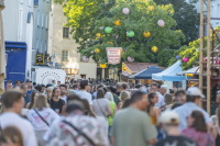 Marktstraße mit mit Foodständen ist unter bunten Lampions voller Menschen.