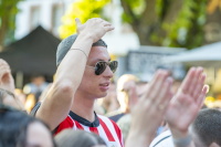 Ein junger Mann mit Sonnenbrille klatscht inmitten eines Publikums.
