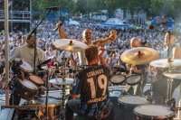 Blick von der Bühne auf Musiker und ein großes Publikum bei einem Open-Air-Konzert.