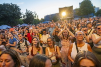 Publikum klatscht bei Sonnenuntergang vor einer Open-Air-Bühne.