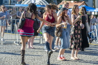 Junge Menschen tanzen und stehen bei einem Open-Air-Konzert vor der Bühne.