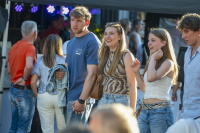 Junge Erwachsene stehen bei einem Fest im Freien vor einer Bühne.