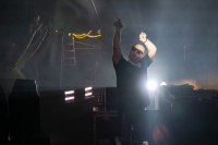 DJ mit Sonnenbrille steht bei Nebel und Bühnenlicht hinter einem Mischpult.