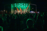 Band spielt nachts auf einer grün beleuchteten Bühne vor Publikum.