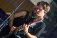 Gitarrist spielt auf einer Bühne, im Hintergrund steht ein weiterer Musiker.